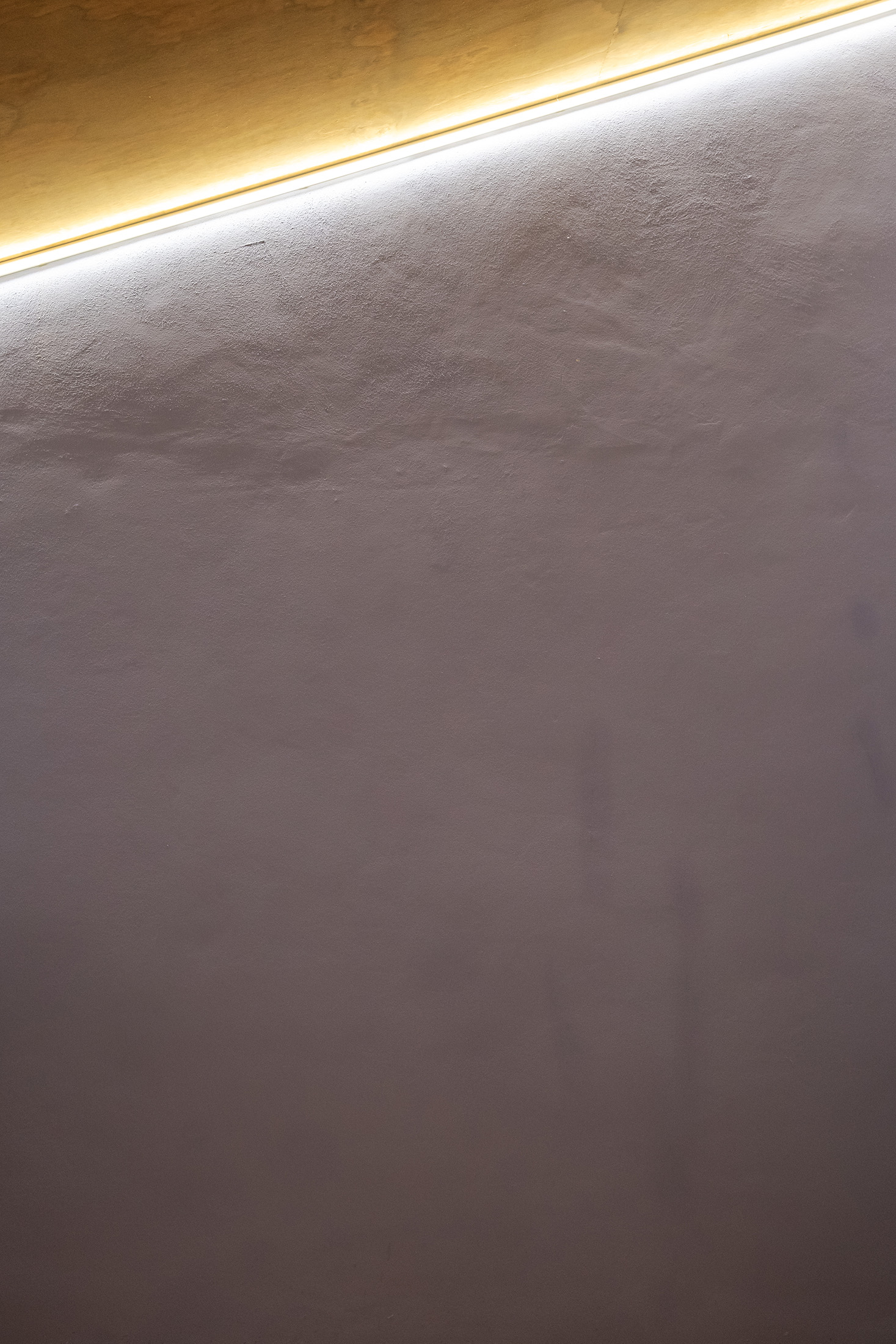 Detalle de la iluminación indirecta LED resaltando la textura de los muros blancos